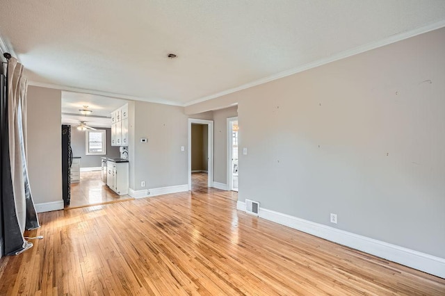 unfurnished living room with light wood-style flooring, baseboards, a ceiling fan, and visible vents