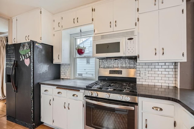 kitchen with white microwave, dark countertops, black refrigerator with ice dispenser, decorative backsplash, and stainless steel range with gas cooktop