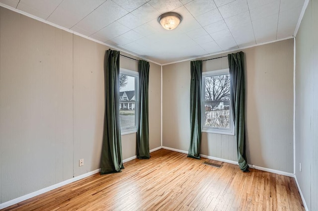 unfurnished room featuring crown molding, visible vents, a wealth of natural light, and light wood finished floors