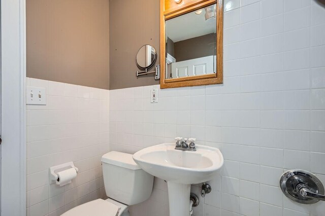 bathroom with tile walls and toilet