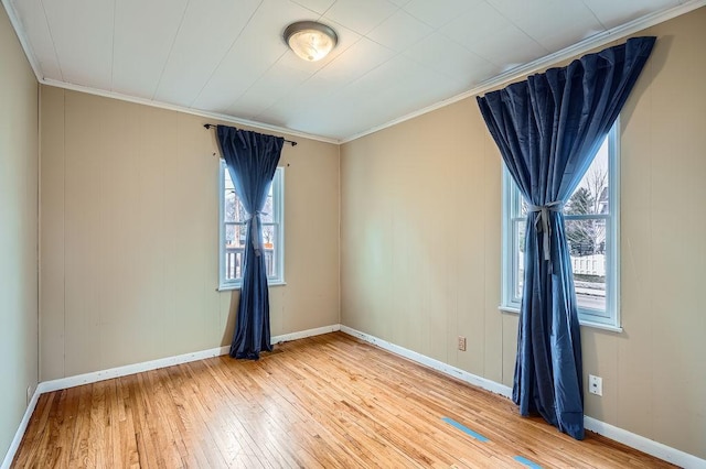 empty room with crown molding, baseboards, and light wood-type flooring