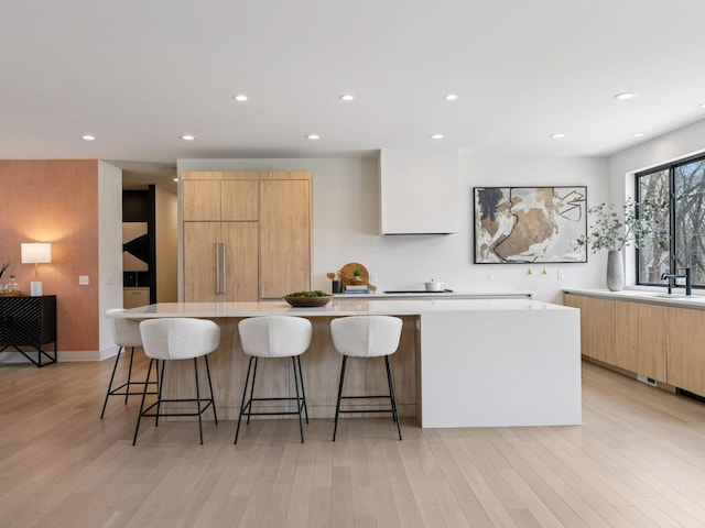 251 Glenbrook Rd N, Wayzata, MN 55391 - kitchen with modern cabinets, light wood finished floors, a large island, a breakfast bar area, and recessed lighting
