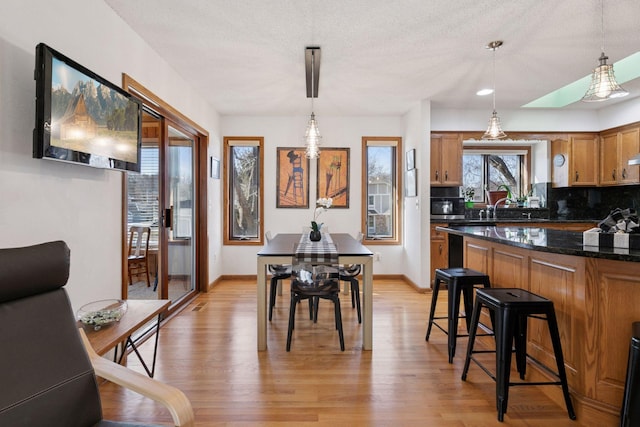 1001 Gramsey Pl, Burnsville, MN 55306 - kitchen featuring light wood finished floors, decorative backsplash, a breakfast bar, brown cabinets, and a textured ceiling