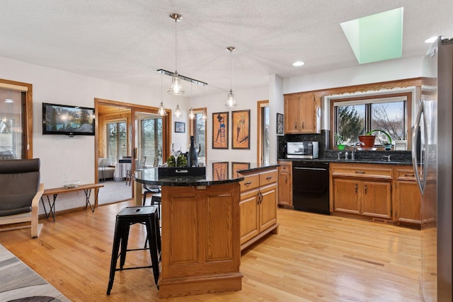 1001 Gramsey Pl, Burnsville, MN 55306 - kitchen featuring appliances with stainless steel finishes, a kitchen bar, a center island, light wood-type flooring, and a sink