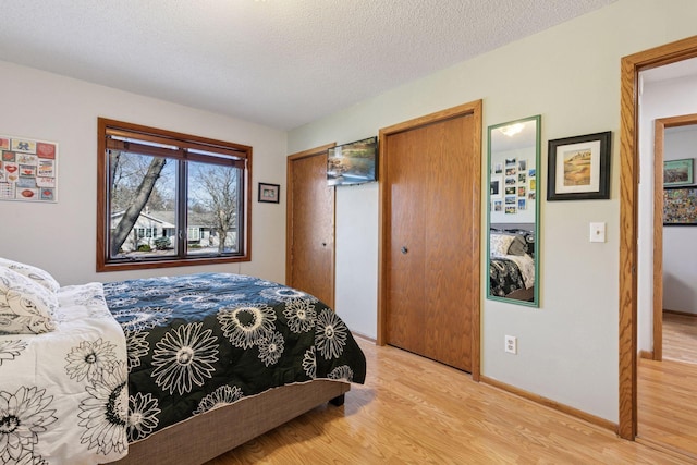 1001 Gramsey Pl, Burnsville, MN 55306 - bedroom featuring light wood-style floors, baseboards, a textured ceiling, and multiple closets