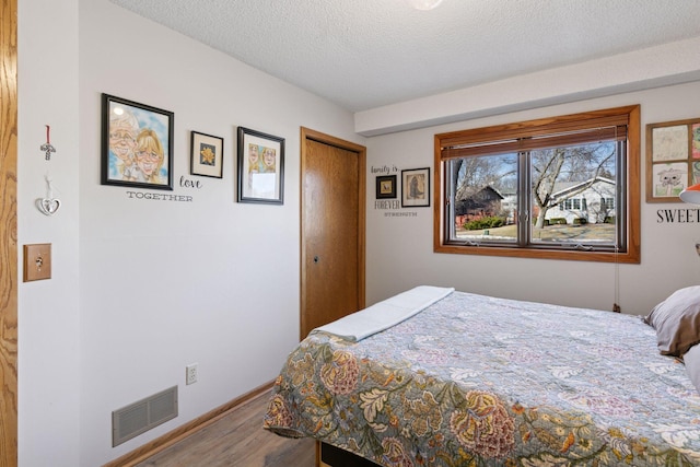 1001 Gramsey Pl, Burnsville, MN 55306 - bedroom with wood finished floors, a textured ceiling, a closet, and baseboards