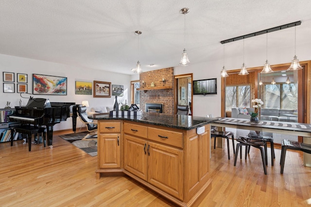 1001 Gramsey Pl, Burnsville, MN 55306 - kitchen featuring open floor plan, a brick fireplace, light wood-type flooring, a textured ceiling, and decorative light fixtures