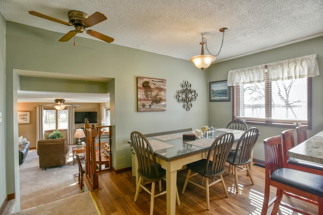 dining area with baseboards, a ceiling fan, a textured ceiling, and wood finished floors