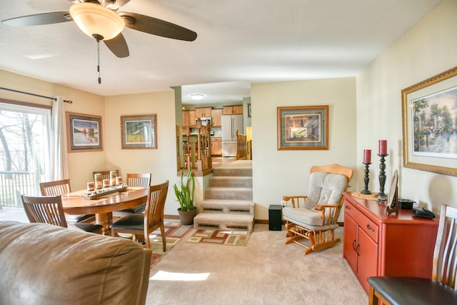 dining area featuring stairway, ceiling fan, and light colored carpet