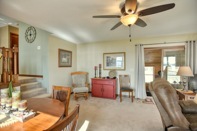 dining area featuring a ceiling fan, stairs, and light colored carpet