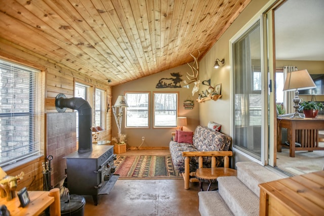 sitting room with unfinished concrete floors, wood ceiling, vaulted ceiling, and a wood stove
