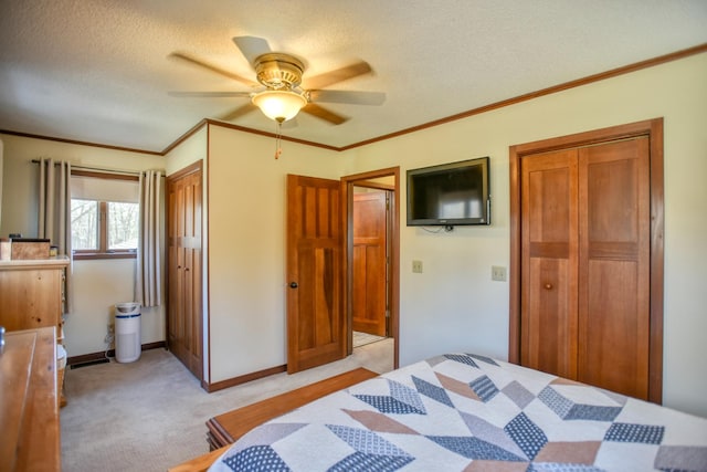 bedroom featuring ornamental molding, baseboards, ceiling fan, light colored carpet, and a textured ceiling