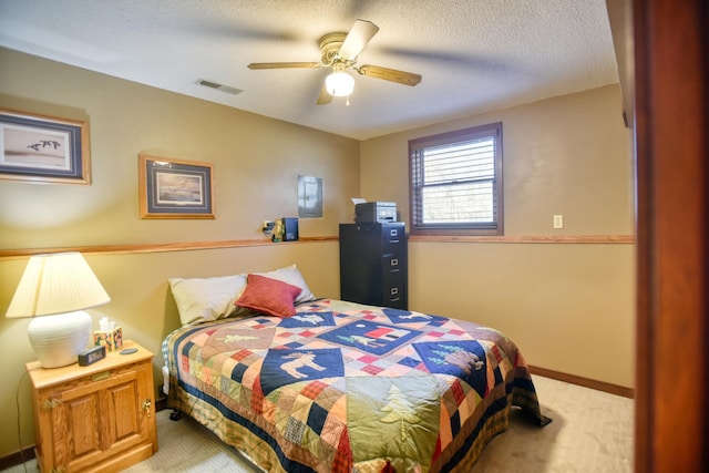 bedroom with a ceiling fan, a textured ceiling, visible vents, and light carpet