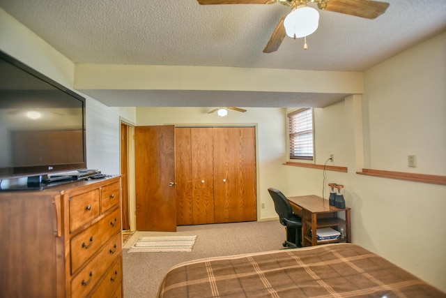 carpeted bedroom featuring a ceiling fan, a closet, and a textured ceiling