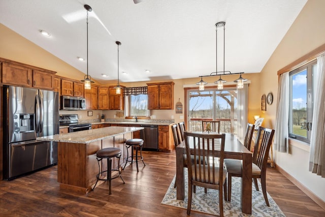 kitchen with brown cabinetry, a center island, lofted ceiling, and stainless steel appliances