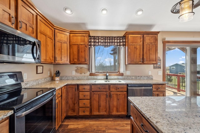 kitchen with a sink, appliances with stainless steel finishes, recessed lighting, and brown cabinets