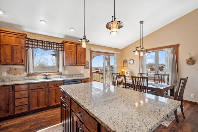 kitchen with a sink, a kitchen island, vaulted ceiling, and brown cabinets