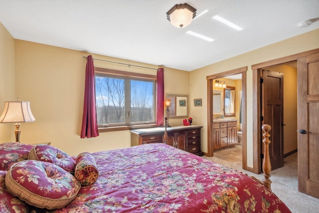 bedroom with a sink, ensuite bath, and light carpet