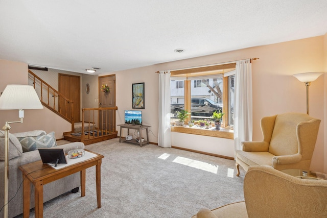 carpeted living area with stairs, visible vents, and baseboards
