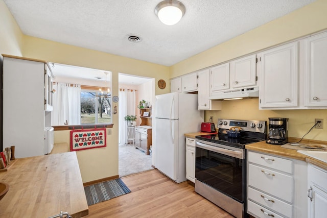 kitchen with freestanding refrigerator, stainless steel electric range oven, white cabinetry, visible vents, and under cabinet range hood