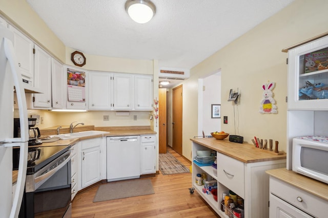 kitchen with a sink, white cabinets, white appliances, and light wood-style flooring