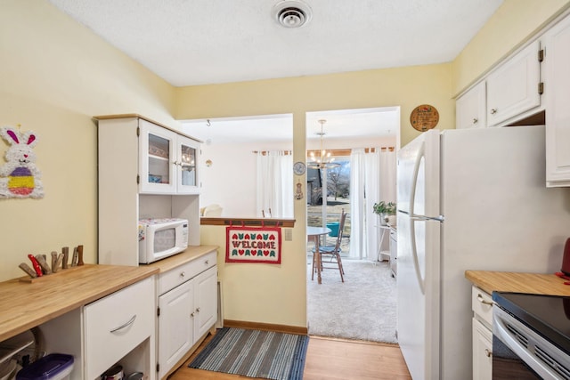 kitchen featuring white microwave, light wood-style flooring, white cabinetry, visible vents, and a notable chandelier