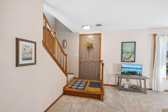 entryway with light colored carpet, baseboards, visible vents, and stairs