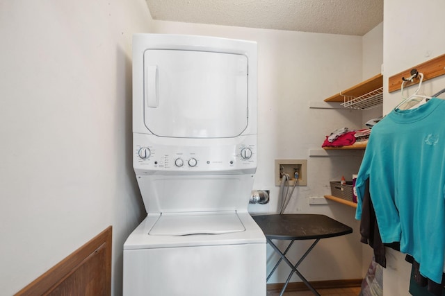 laundry area featuring laundry area, a textured ceiling, and stacked washer and clothes dryer