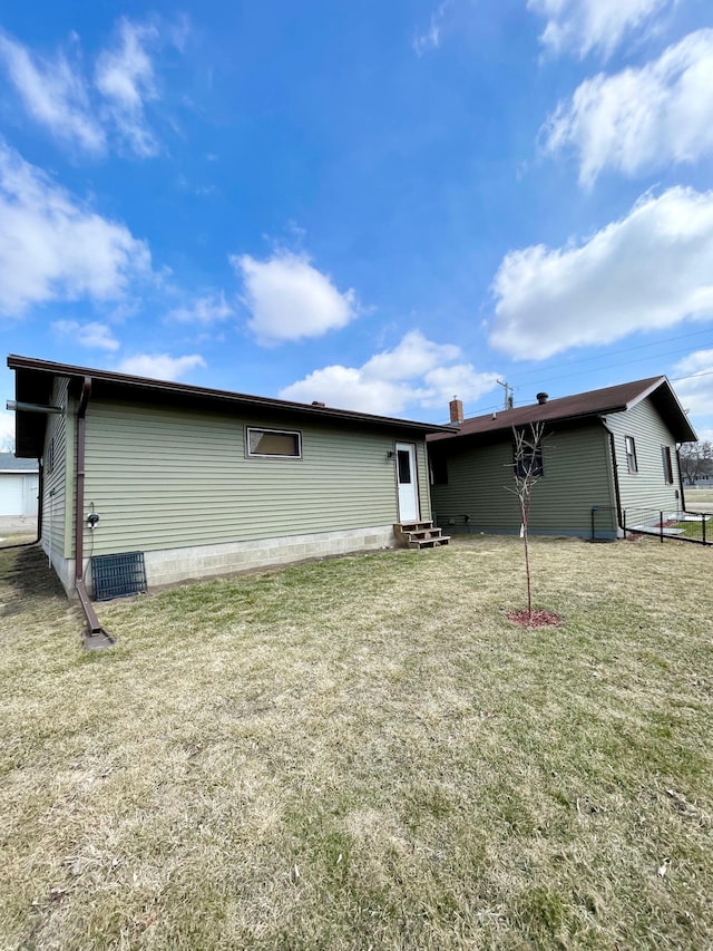 rear view of property featuring entry steps and a lawn