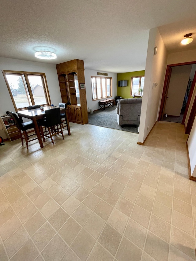 dining room featuring a textured ceiling, light tile patterned floors, and baseboards