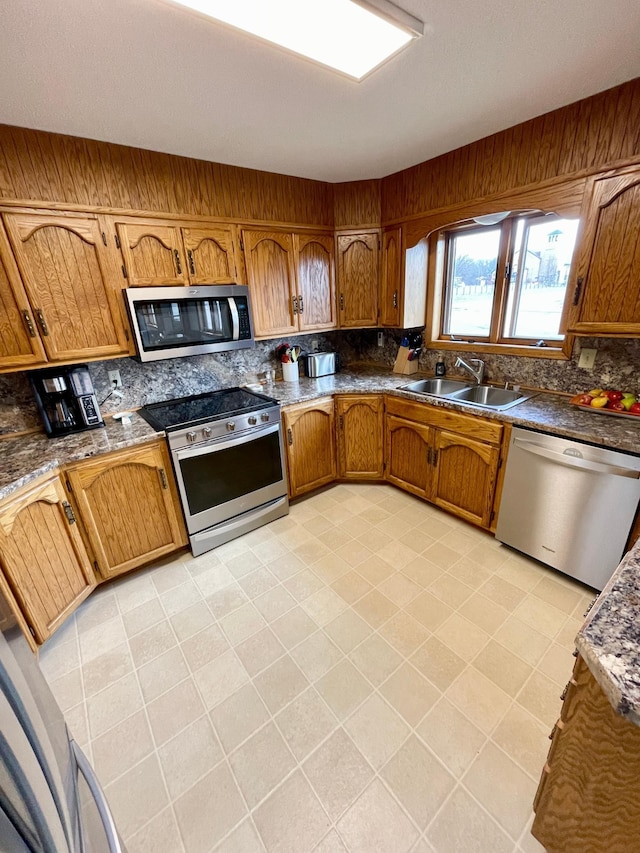 kitchen with a sink, brown cabinetry, decorative backsplash, and stainless steel appliances