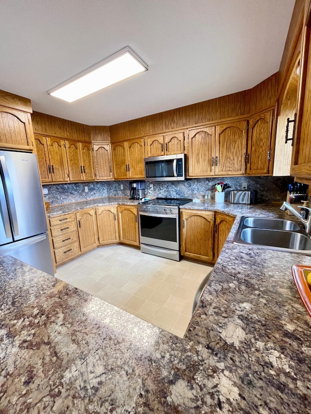 kitchen with brown cabinets, a sink, backsplash, and stainless steel appliances