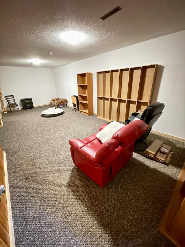 living area featuring carpet, visible vents, a textured ceiling, and baseboards