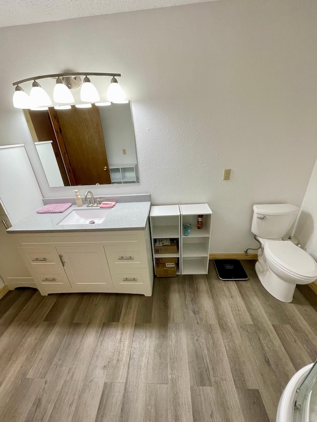 bathroom with toilet, baseboards, vanity, and wood finished floors