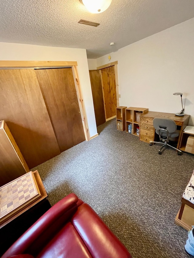 home office featuring visible vents, carpet flooring, and a textured ceiling