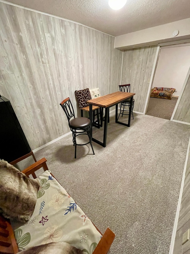 office area featuring a textured ceiling, wooden walls, baseboards, and carpet