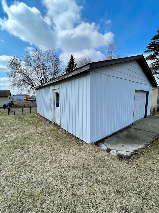 view of side of home with a garage, fence, an outdoor structure, and a lawn
