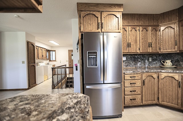 123 3rd St, Bluffton, MN 56518 - kitchen featuring stainless steel refrigerator with ice dispenser, washer and dryer, backsplash, light tile patterned floors, and brown cabinets