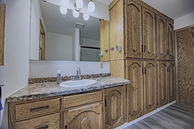 123 3rd St, Bluffton, MN 56518 - full bathroom with a textured ceiling, wood finished floors, vanity, and an enclosed shower