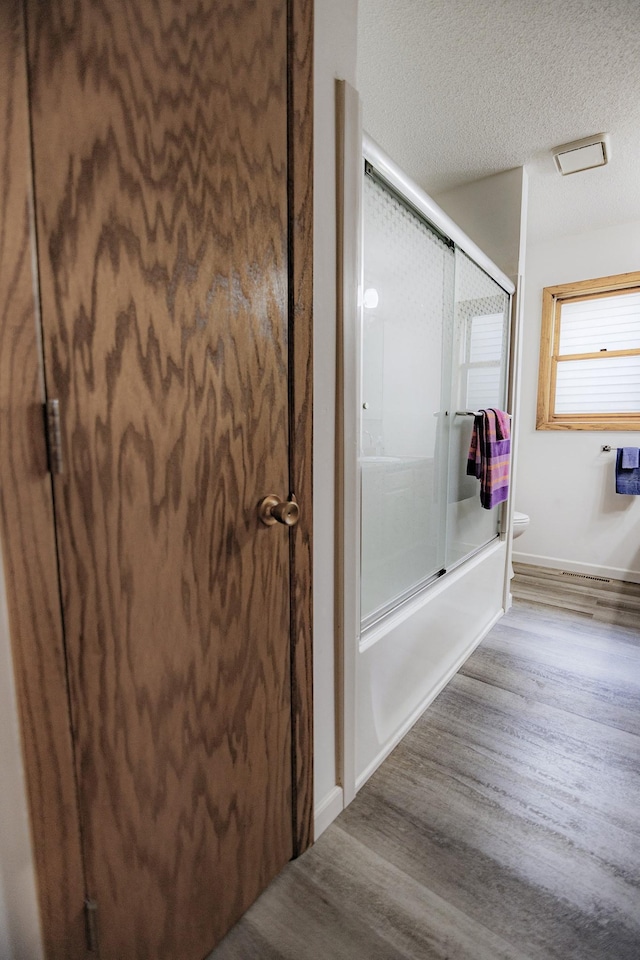 123 3rd St, Bluffton, MN 56518 - full bathroom with shower / bath combination with glass door, wood finished floors, and a textured ceiling