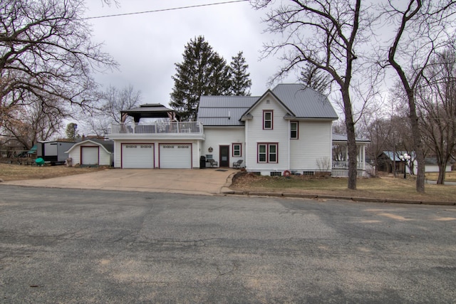 view of front of house with a balcony, a storage unit, driveway, an outbuilding, and metal roof