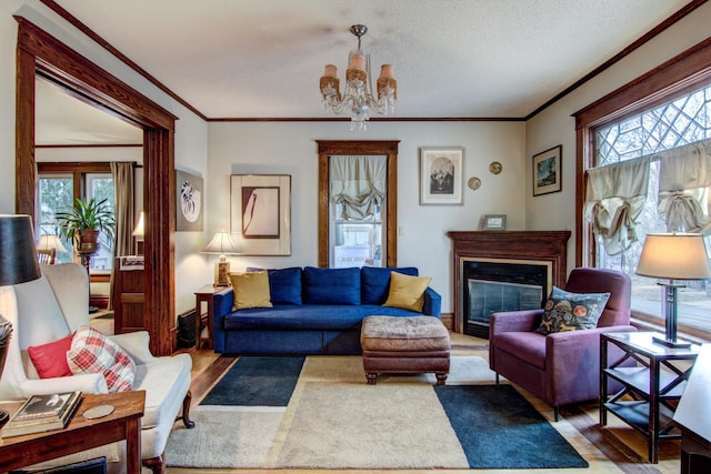 living area featuring crown molding, a chandelier, wood finished floors, and a healthy amount of sunlight