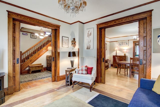 sitting room featuring stairway, a chandelier, crown molding, and light wood finished floors