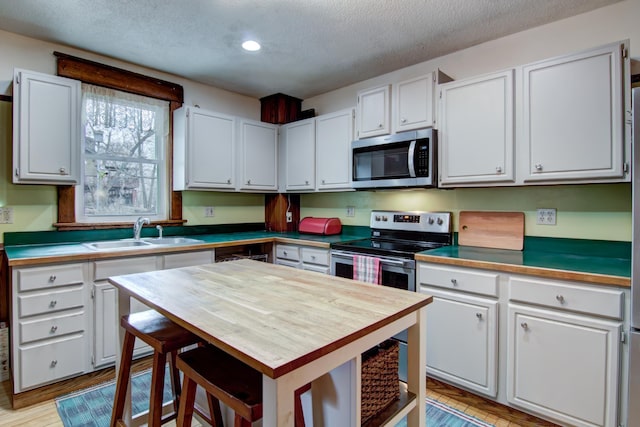 kitchen featuring white cabinets, a textured ceiling, stainless steel appliances, and a sink