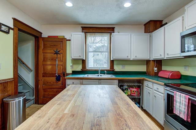 kitchen featuring a sink, white cabinetry, appliances with stainless steel finishes, butcher block counters, and recessed lighting