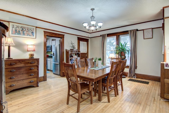 dining room featuring ornamental molding, baseboards, visible vents, light wood-style flooring, and a notable chandelier