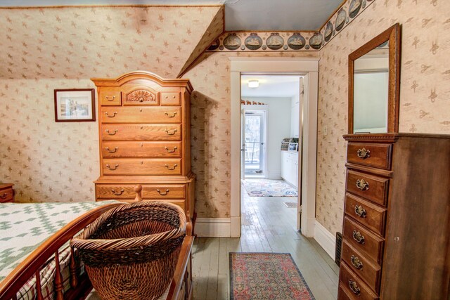 bedroom featuring wood-type flooring, baseboards, and wallpapered walls