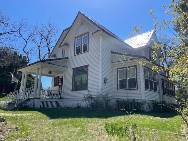 view of property exterior with covered porch and a lawn