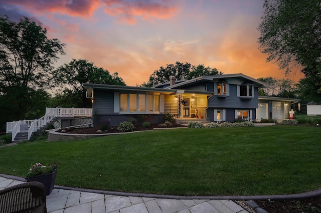 108 1st St, Kenyon, MN 55946 - split level home featuring a front lawn, brick siding, a chimney, and a wooden deck