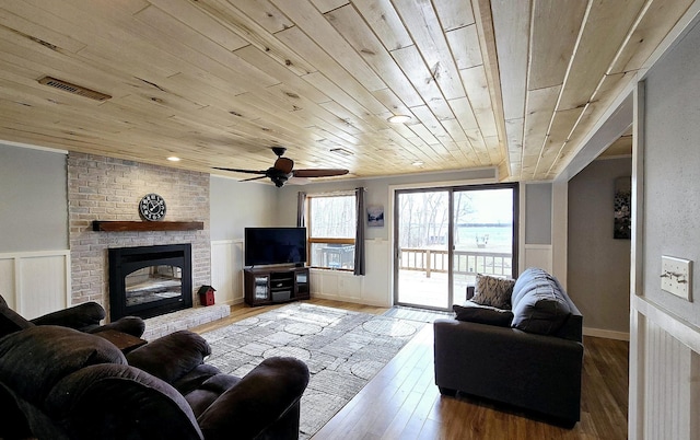 22004 Old Curry Rd SE, Cass Lake, MN 56633 - living area with a wainscoted wall, wooden ceiling, a fireplace, wood finished floors, and a ceiling fan